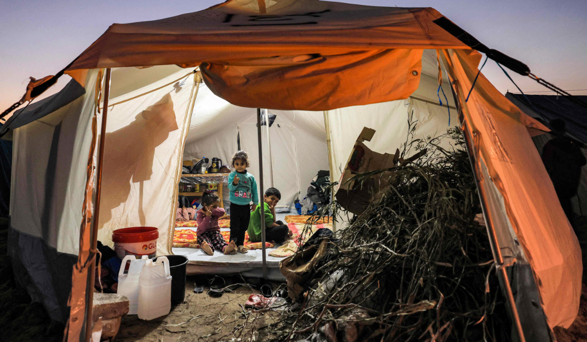 Firewood is placed at the entrance of a tent where children are sitting, at a camp housing Palestinians displaced by the conflict in Gaza between Israel and the Palestinian Hamas movement, in Rafah in the southern Gaza Strip on December 18, 2023. (AFP)