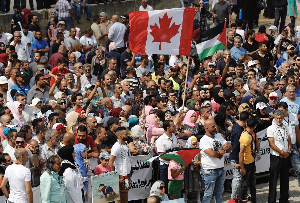Hundreds of Palestinian refugees waving Palestinian and Canadian flags request asylum at a rally outside the the Canadian Embassy, in Beirut, Lebanon. (AP/File)