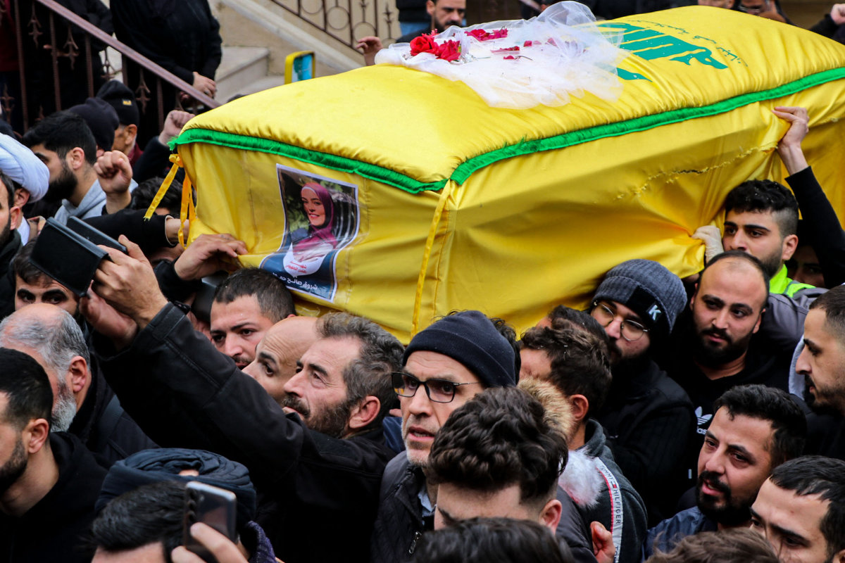 Mourners carry the coffin of a woman who was killed together with a Hezbollah fighter in Israeli bombardment on December 27, 2023, in Bint Jbeil, southern Lebanon. (AFP)