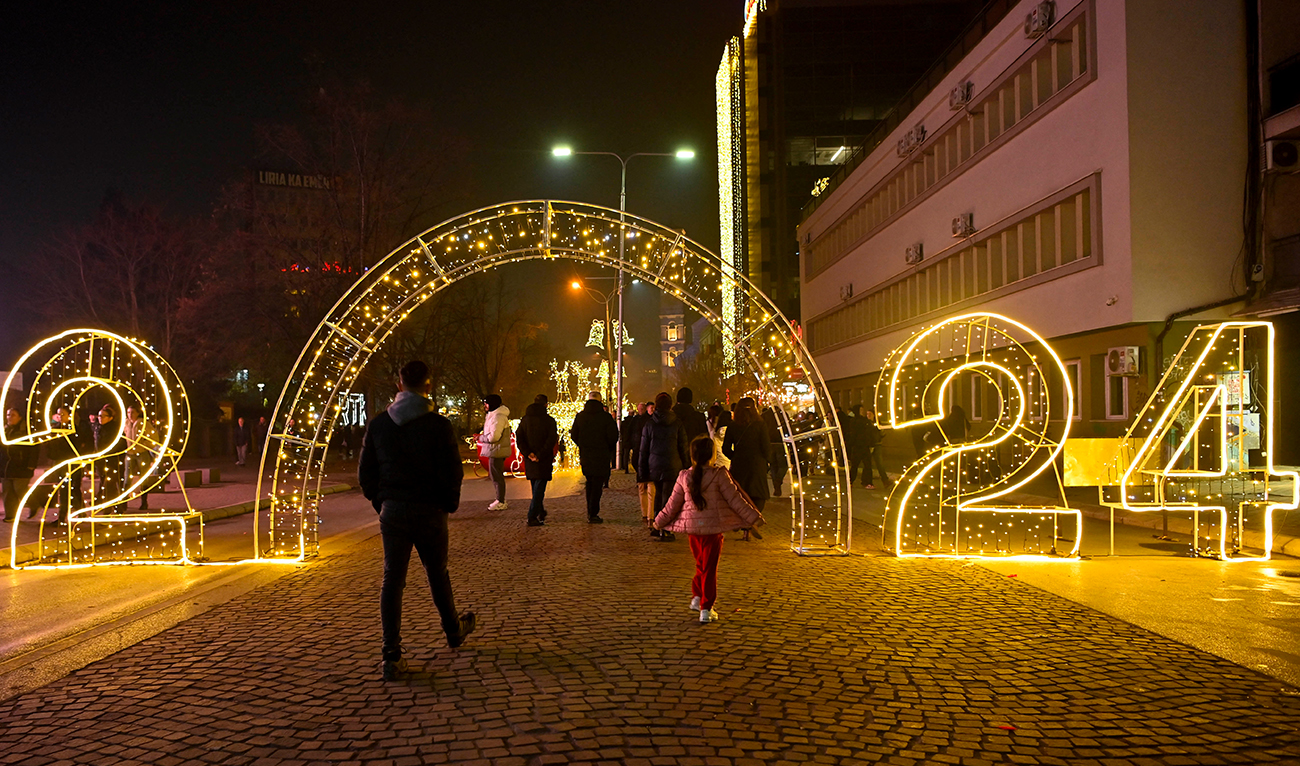 Pedestrians walk through a 2024 illuminated sign displayed in downtown Pristina on December 30, 2023, ahead of the New Year celebrations in Kosovo. (AFP)