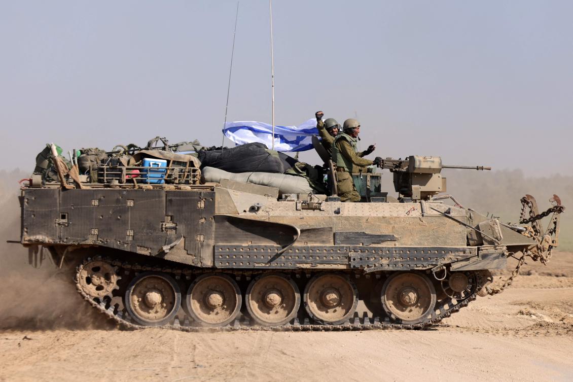 Israeli soldiers on an armoured personnel carrier (APC) waving an Israeli flag as they roll back from the Gaza Strip, amid continuing battles between Israel and the militant group Hamas. (AFP)