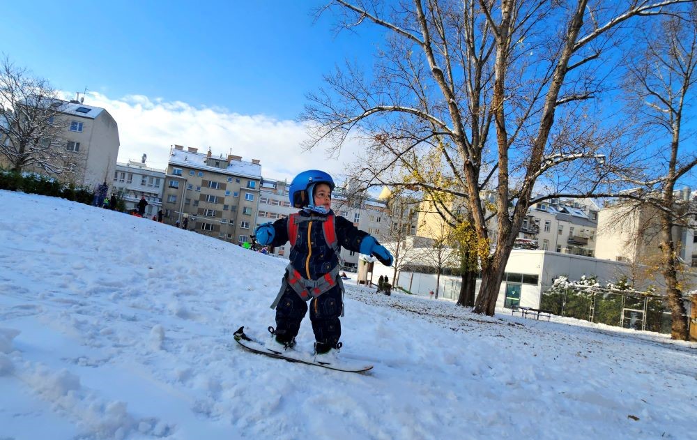 A two-year-old boy snowboards in Steinhage Park, Vienna, Austria, Dec. 3, 2023, as Vienna's landscape changes to a winter aspect. (AFP)