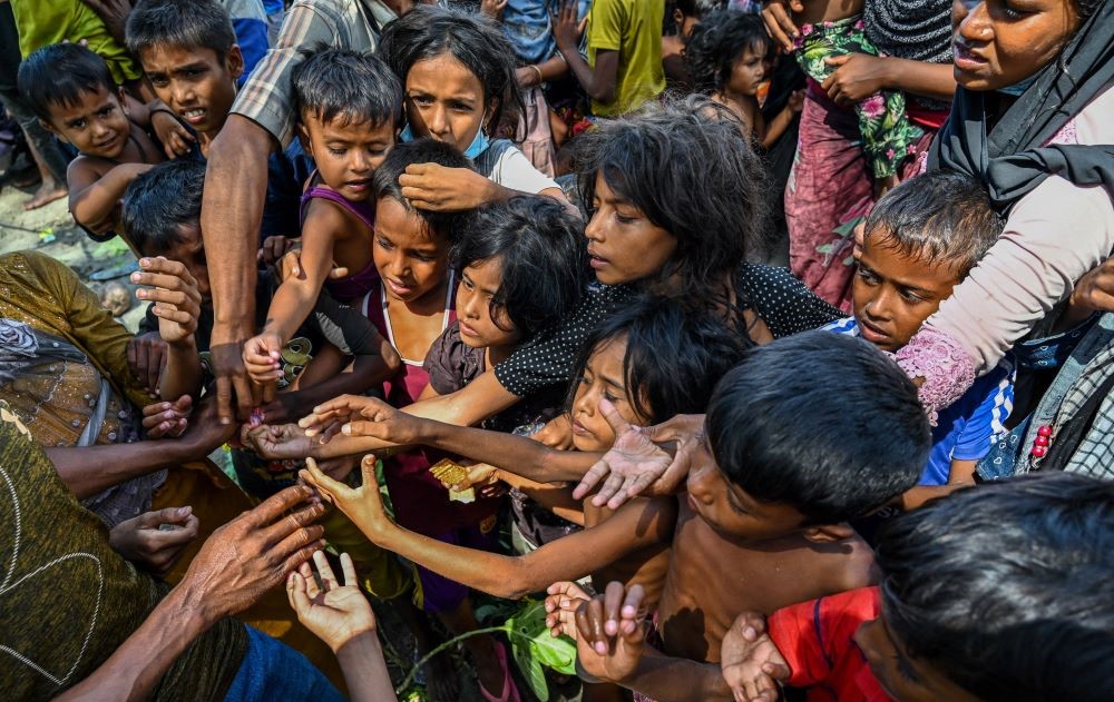 Newly-arrived Rohingya refugees receive food donated by people at a beach in Laweueng, Pidie district, Indonesia's Aceh province, Dec. 10, 2023. (AFP)