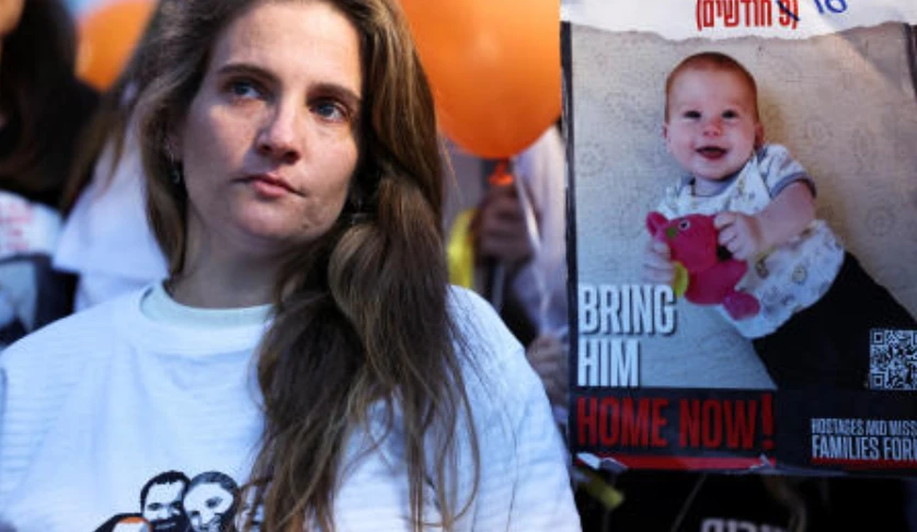A protestor stands next to a sign calling for the release of Kfir Bibas, 10 months, during a protest calling for the immediate release of hostages, in Tel Aviv on Nov. 28, 2023. (Reuters)