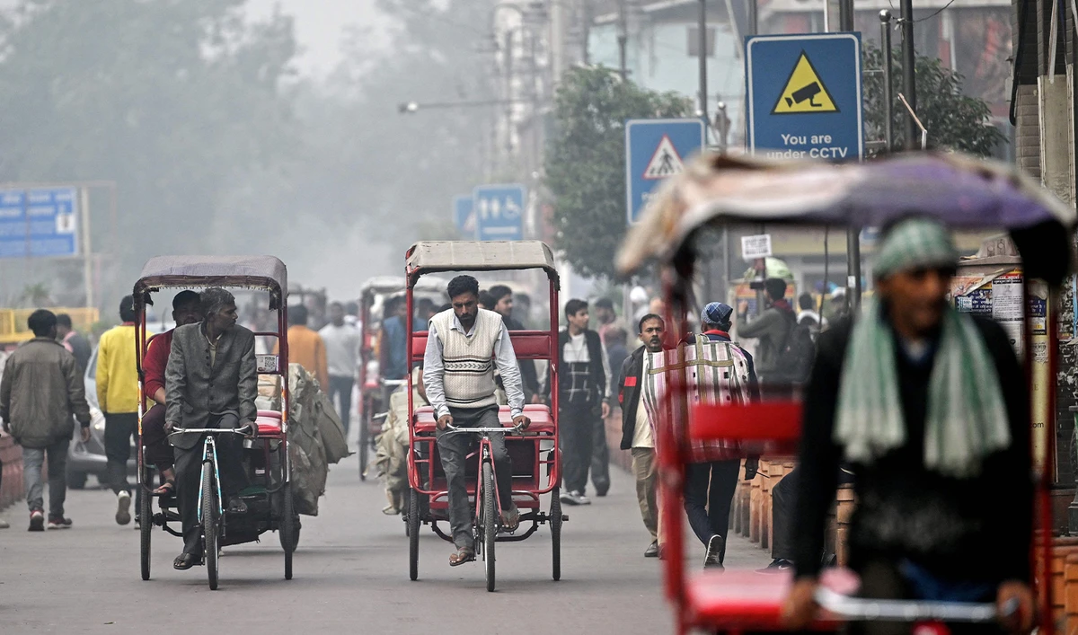 In this picture taken on November 30, 2023, Rizwan (C) pedals a tricycle rickshaw as he looks for customers amid dense smog, along a street in the old quarters of New Delhi. (AFP)