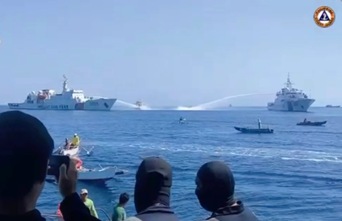 In this image taken from video provided by the Philippine Coast Guard, two Chinese Coast Guard ships aim their water cannons on a Philippine Bureau of Fisheries and Aquatic Resources (BFAR) vessel, center, as it approaches Scarborough Shoal in the disputed South China Sea on Saturday Dec. 9, 2023. (Philippine Coast Guard via AP)