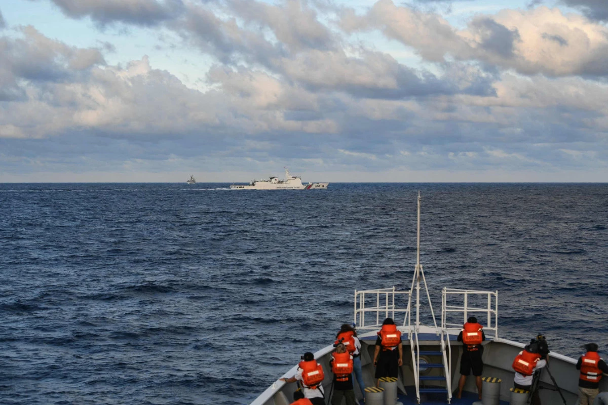 Journalists onboard the Philippine Coast Guard ship 'Melchora Aquino' take video and photos of a Chinese Coast Guard ship (C) sailing near a Philippine vessel (L) that was part of a convoy of civilian boats in the disputed South China Sea on December 10, 2023. (AFP)