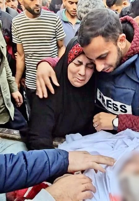 Al Jazeera journalist, Anas Al-Sharif, comforts his mother as they say farewell to his father Jamal Al-Sharif. (@AnasAlSharif0)
