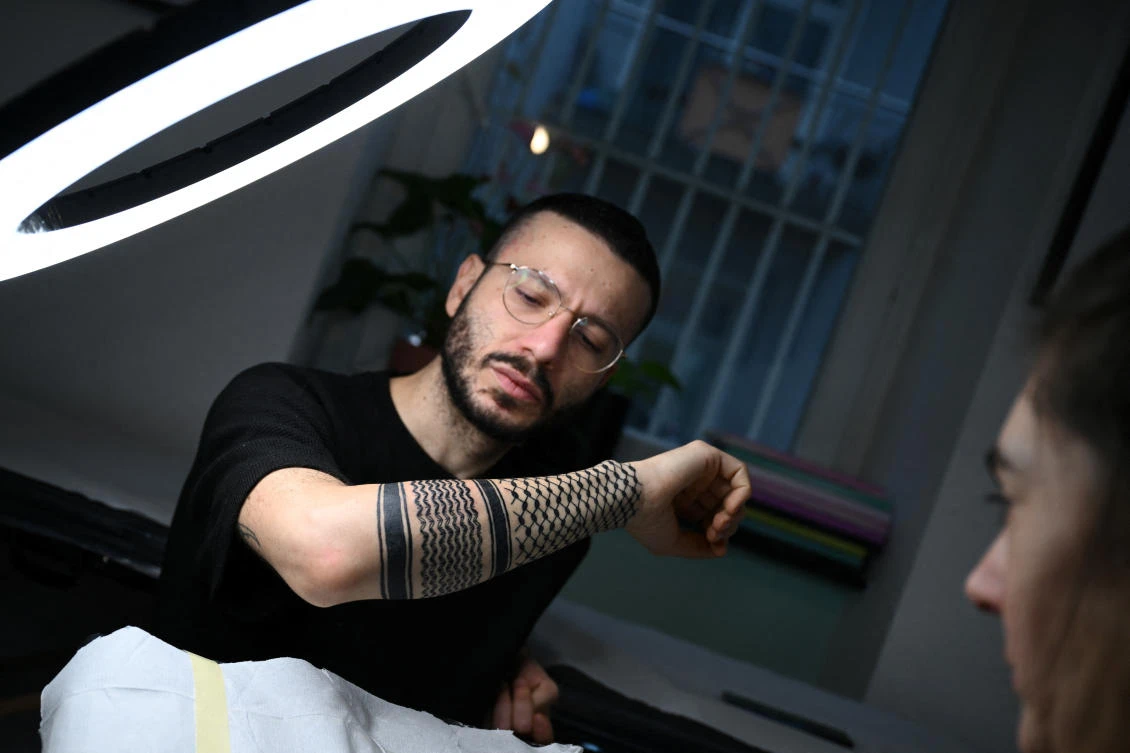Palestinian Syrian poet Ramy Al-Asheq, 34, looks at his forearm which is tattoed with the black-and-white chequerboard pattern of the Palestinian keffiyeh (REUTERS)