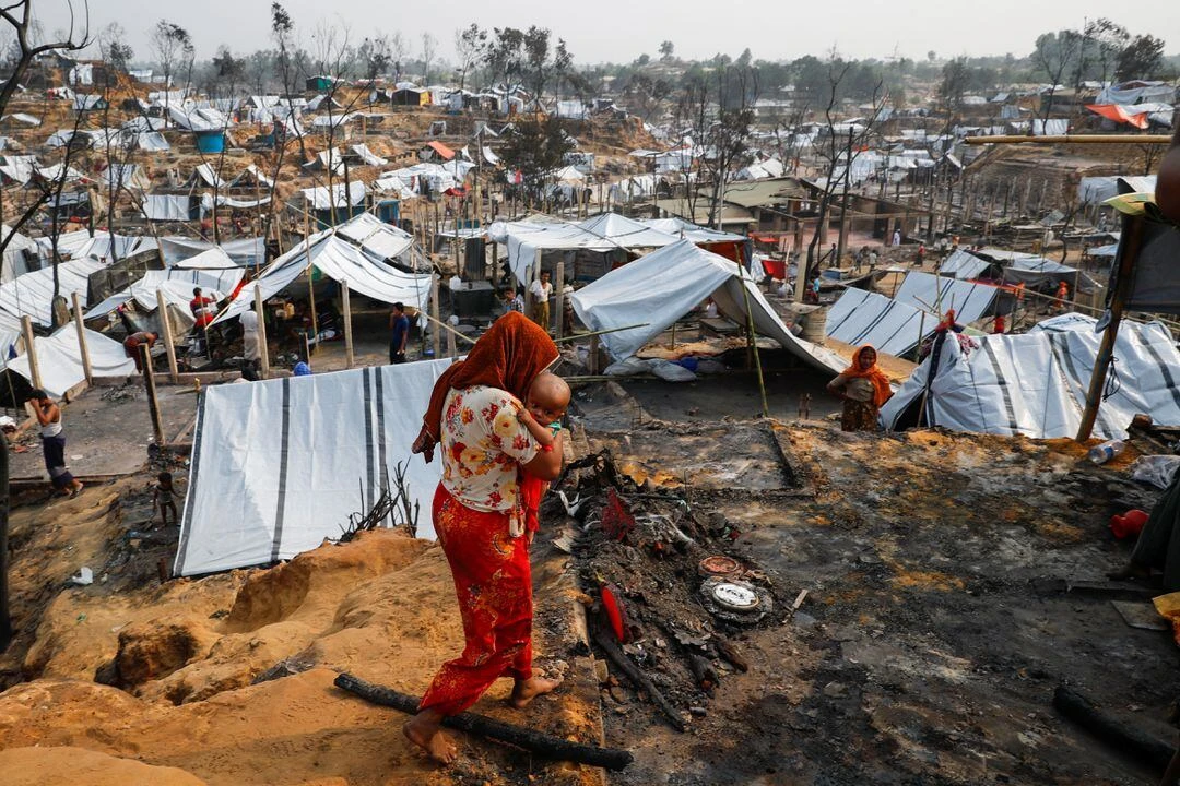 Rohingya refugee woman carries her child after a massive fire broke out in Cox's Bazar, Bangladesh. (File/Reuters)