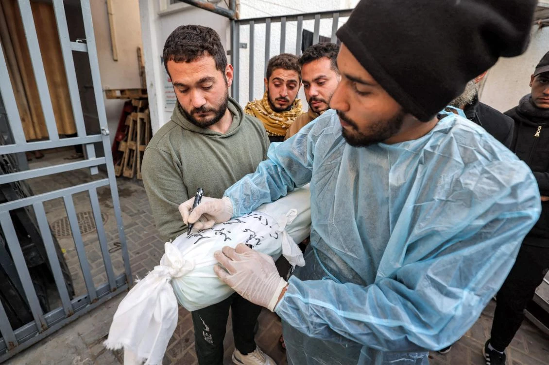 A hospital worker writes the name and information on the body of a Palestinian child who was killed overnight during Israeli bombardment, at a hospital in Rafah in the southern Gaza Strip on Dec. 19, 2023. (AFP)