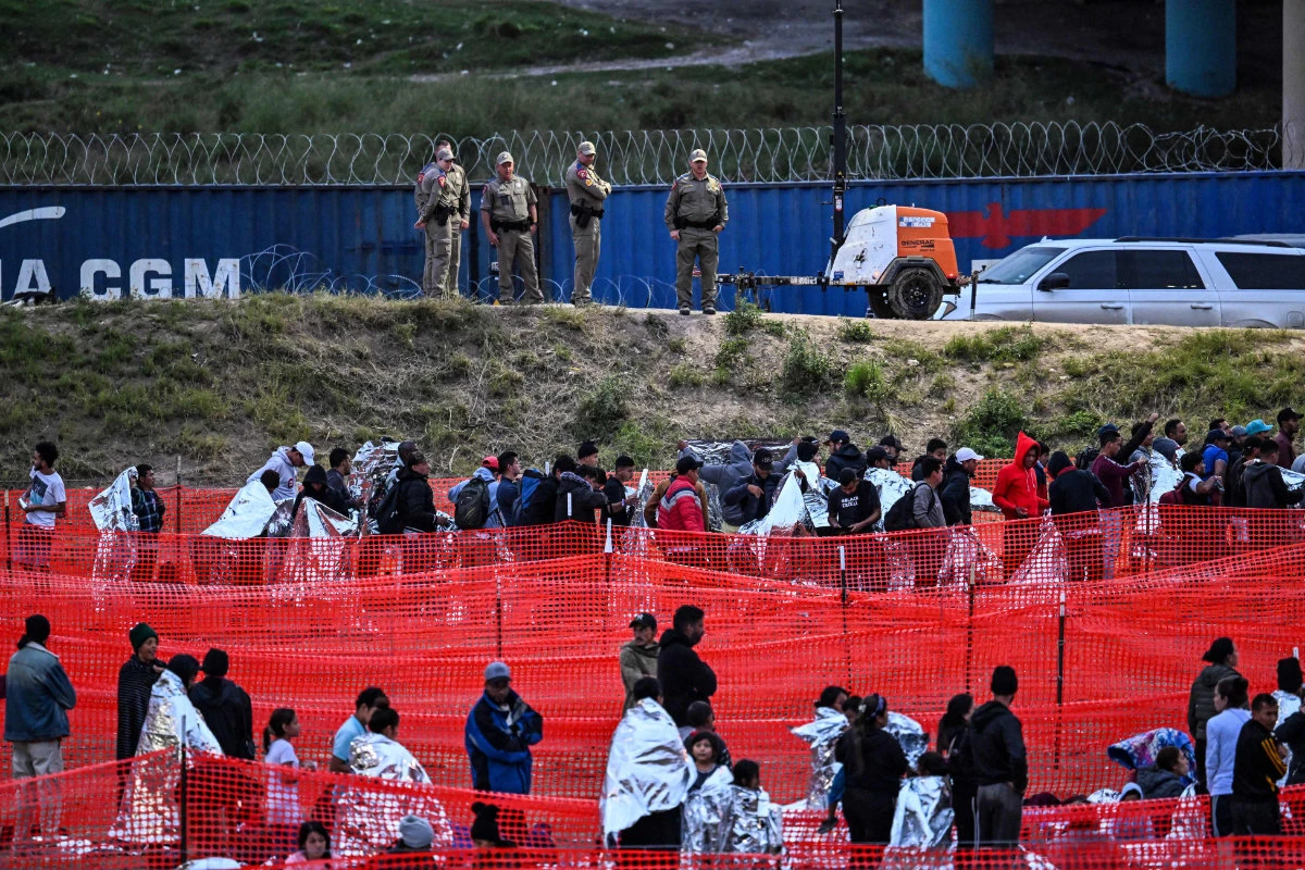 Customs and Border Protection agents stand guard as immigrants wait to be processed at a US Border Patrol transit center after crossing the border from Mexico at Eagle Pass, Texas, on December 22, 2023. (AFP)