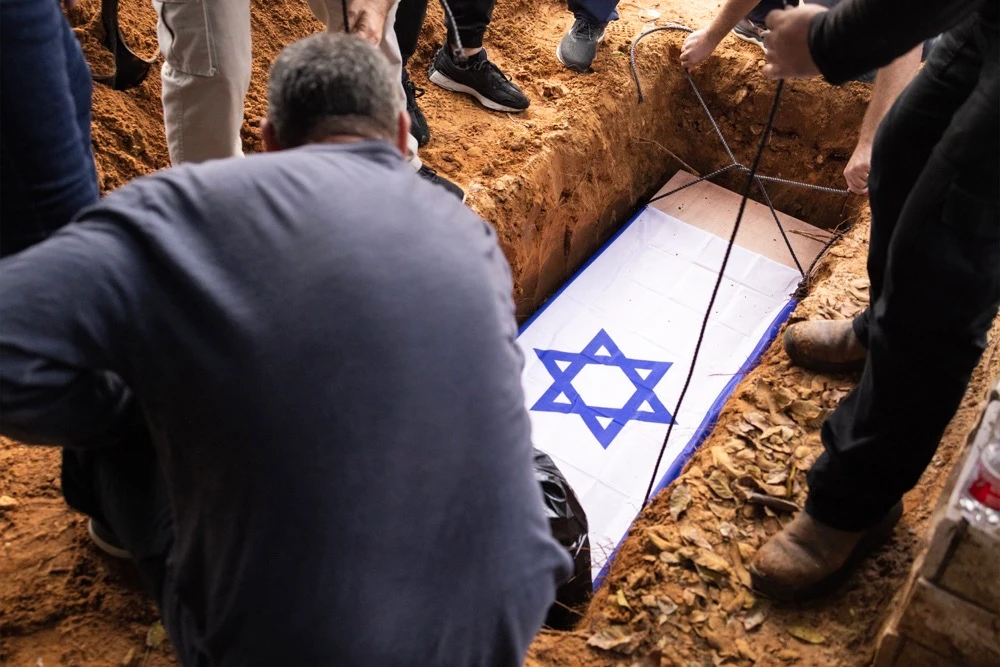 The body of Alon Shamriz, mistakenly killed by Israeli forces in Gaza, is lowered into the grave during the funeral in kibbutz Shefayim near Tel Aviv. (AFP)