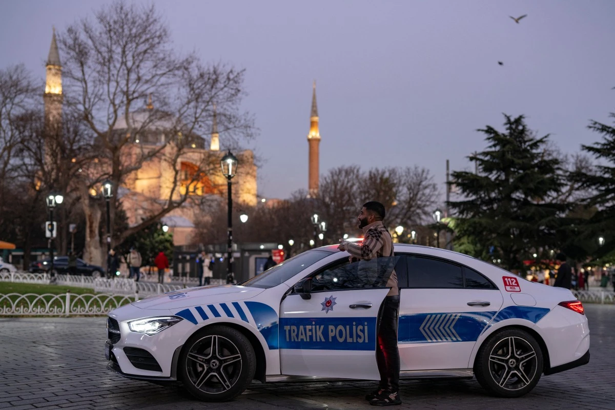 A man poses for a photograph next to a Mercedes converted into a police vehicle, on display at Hagia Sophia Square in Istanbul on December 27, 2023. (AFP)