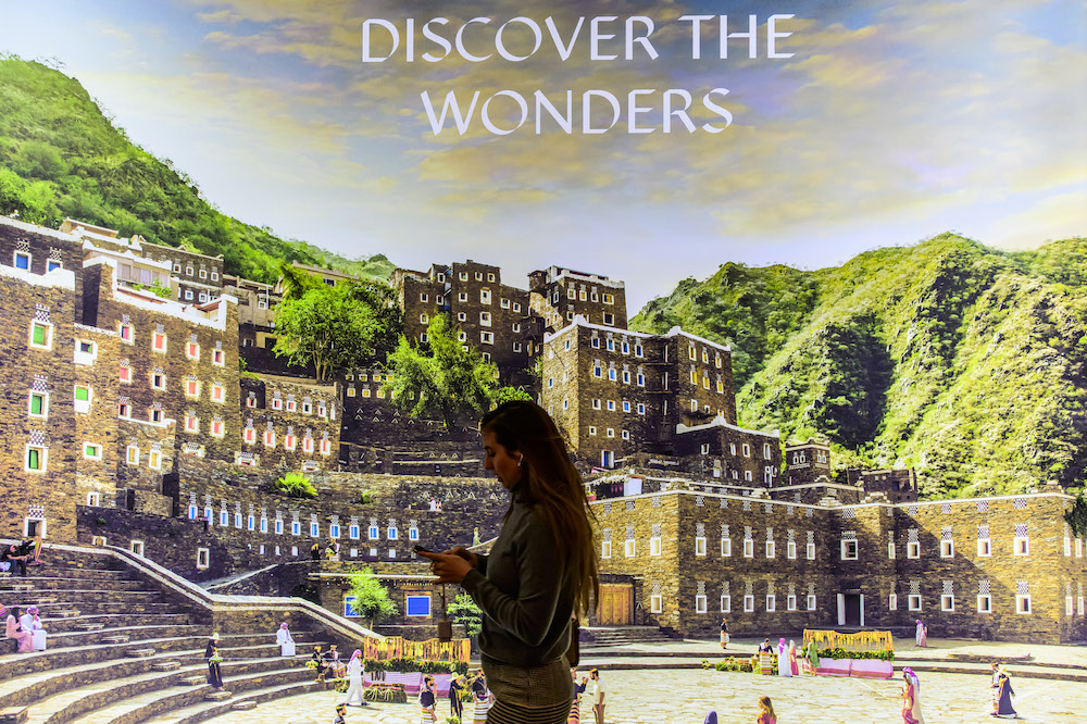 A visitor walks past a billboard at the Saudi Arabia stand at the International Tourism Trade Fair in Berlin on March 8, 2023. (AFP)