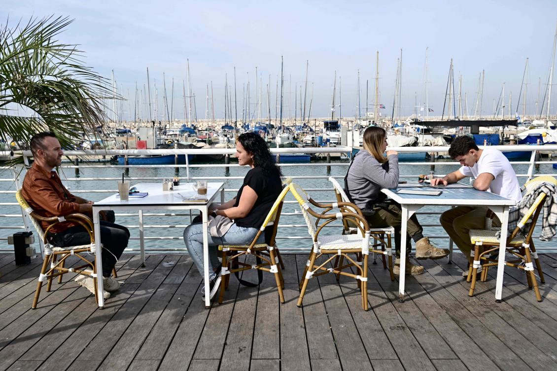People sit at a bar at the marina in the Israeli coastal city of Ashkelon on Jan. 8, 2024, amid continuing battles between Israel and Hamas in Gaza Strip. (AFP)