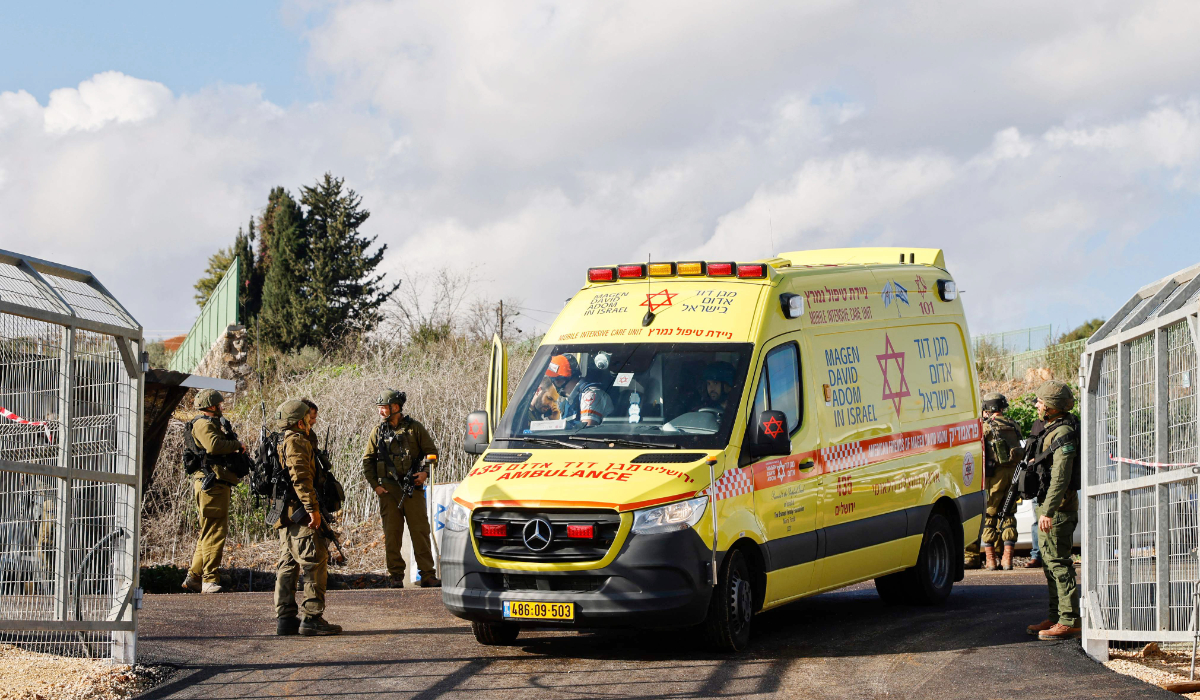 An Israeli ambulance and soldiers are stationed at the entrance of Kfar Yuval in northern Israel near the Lebanon border, after it was reportedly targeted with an anti-tank missile from the Lebanese side on January 14, 2024, amid ongoing cross-border tensions as the war between Israel and the Palestinian Hamas group in Gaza enters its 100th day. (AFP)