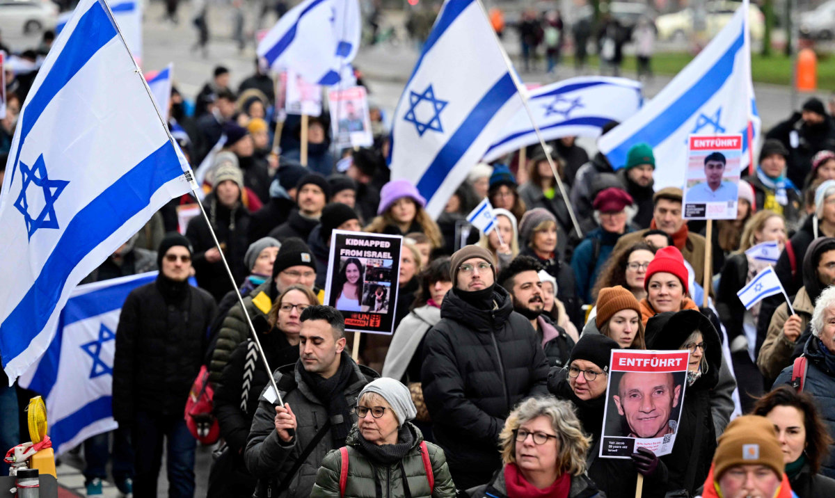Demonstrators wave Israeli flags and hold placards with the portaits of Israeli hostages as they march to mark the 100th day of the hostages' captivity during the ongoing Israeli-Palestinian conflict, on January 14, 2024 in Berlin. (AFP)