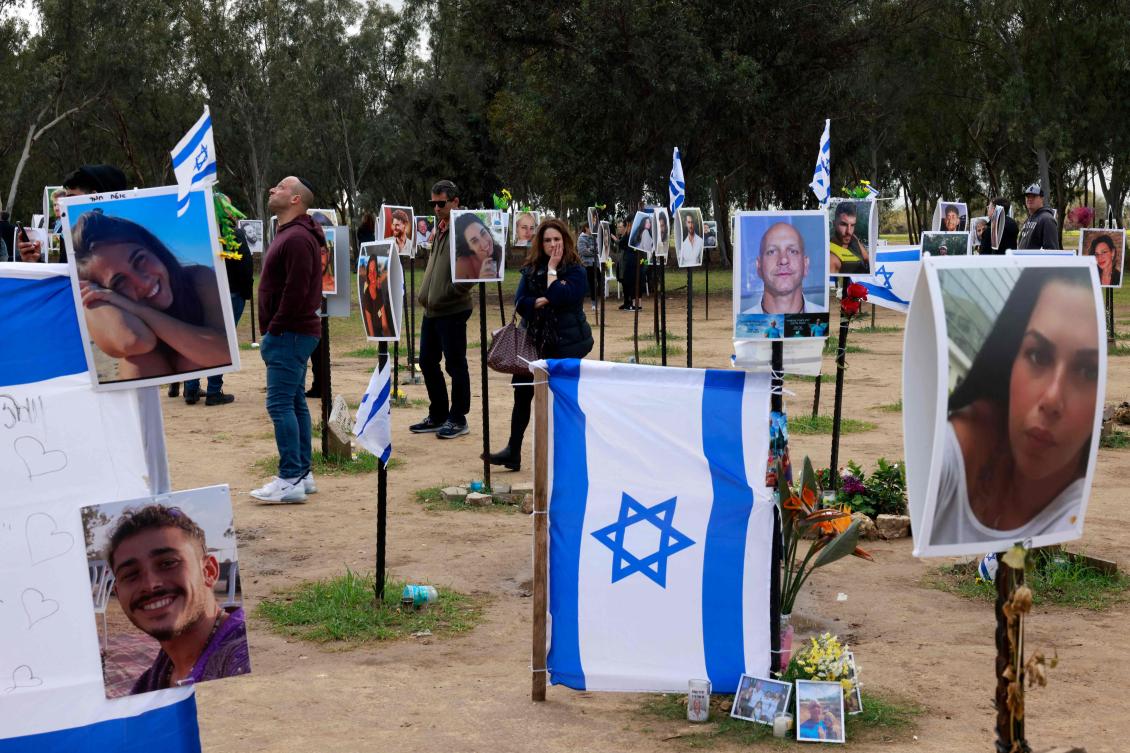 Israelis, including relatives, walk amid national flags and portraits of Israeli hostages held in Gaza since the October 7 attacks, during a visit at the site where the Supernova music festival took place near Kibbutz Reim in southern Israel, on Jan. 14, 2024. (AFP)