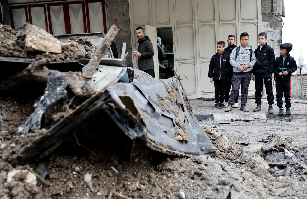 A Palestinian man and children inspect the site of an Israeli strike on a car in Nablus, in the Israeli-occupied West Bank. (Reuters)