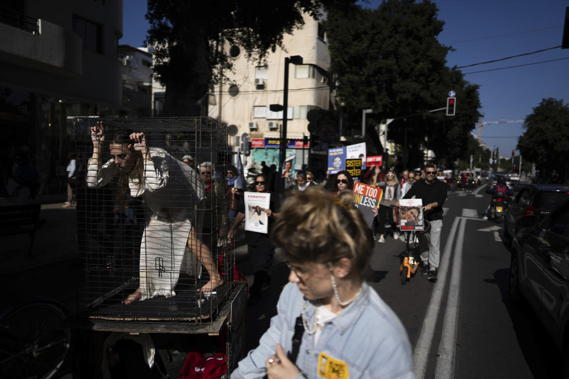 An actress in a cage, relatives and supporters of the Israeli hostages held in the Gaza Strip by Hamas attend a march calling for their release, in Tel Aviv on Jan. 19, 2024. (AP)