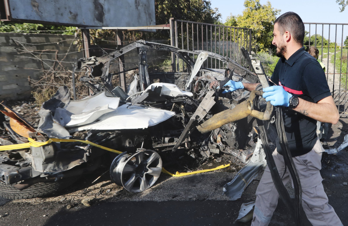 A civil defense worker carries parts of a destroyed car in the southern town of Bazouriyeh, Lebanon, Saturday, Jan. 20, 2024. (AP)
