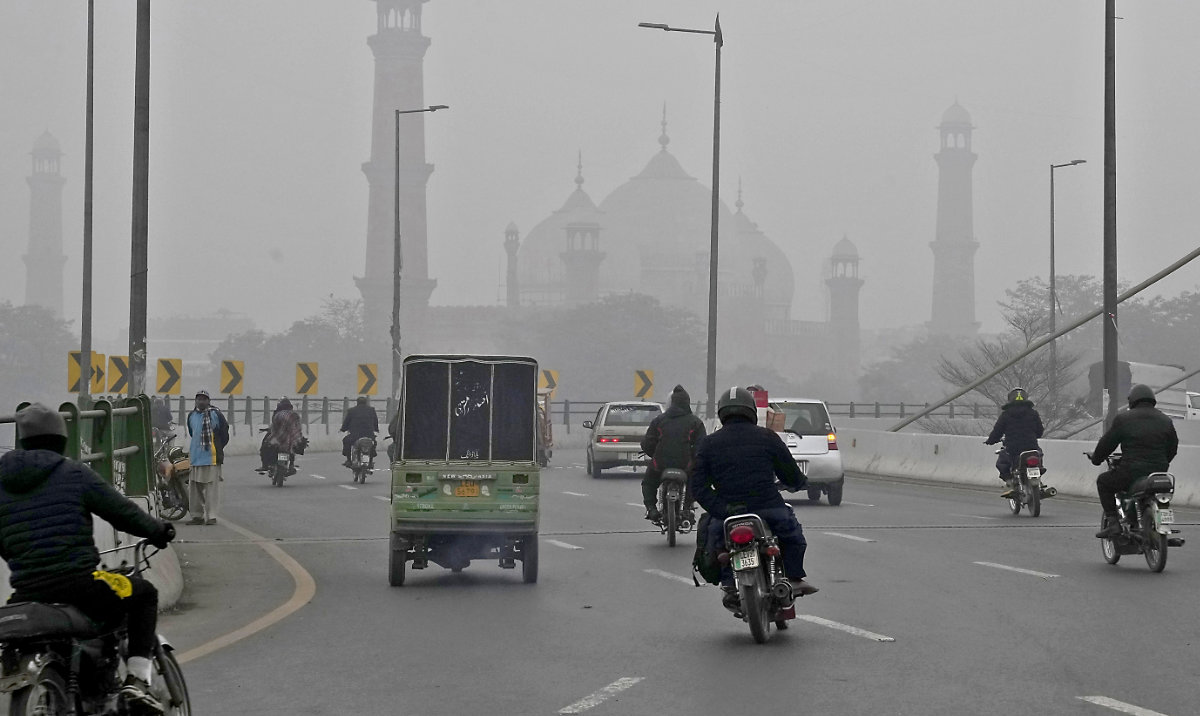 Motorcyclists and vehicles move on a bridge as smog envelops the historical Badshahi Mosque, background, in Lahore, Pakistan, earlier this month. (AP)