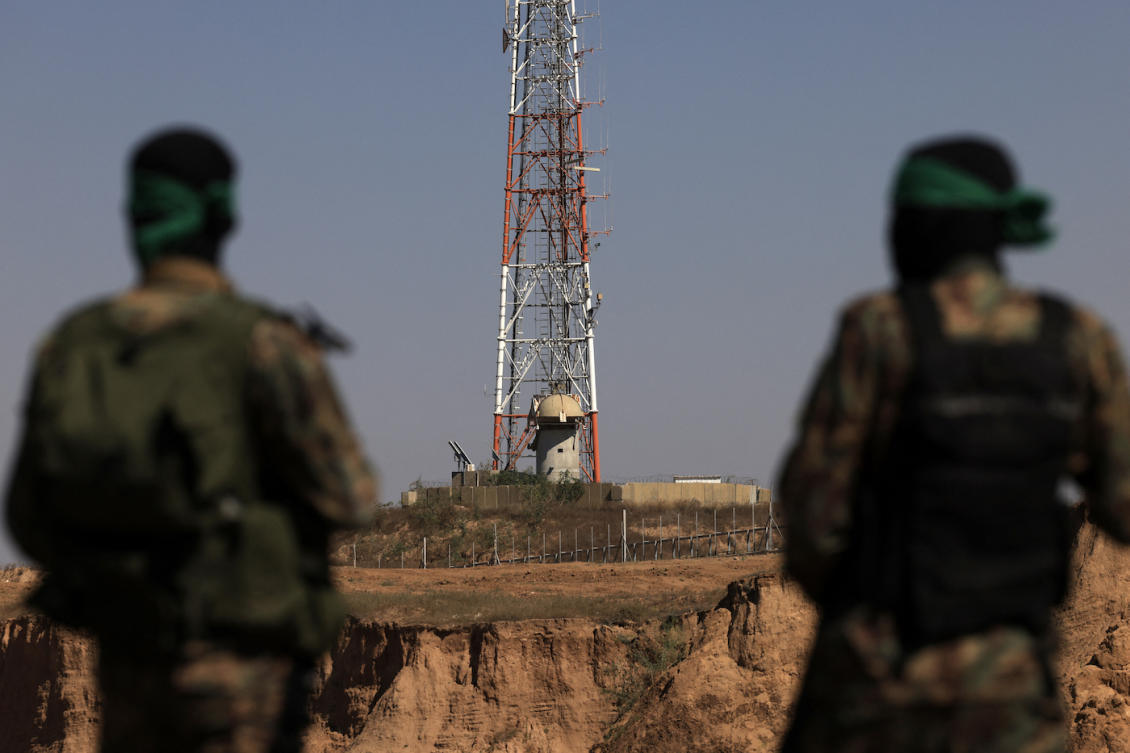 Palestinian fighters of the Al-Qassam Brigades, the armed wing of the Hamas movement, look toward an Israeli army position and surveillance antenna. (File/AFP)
