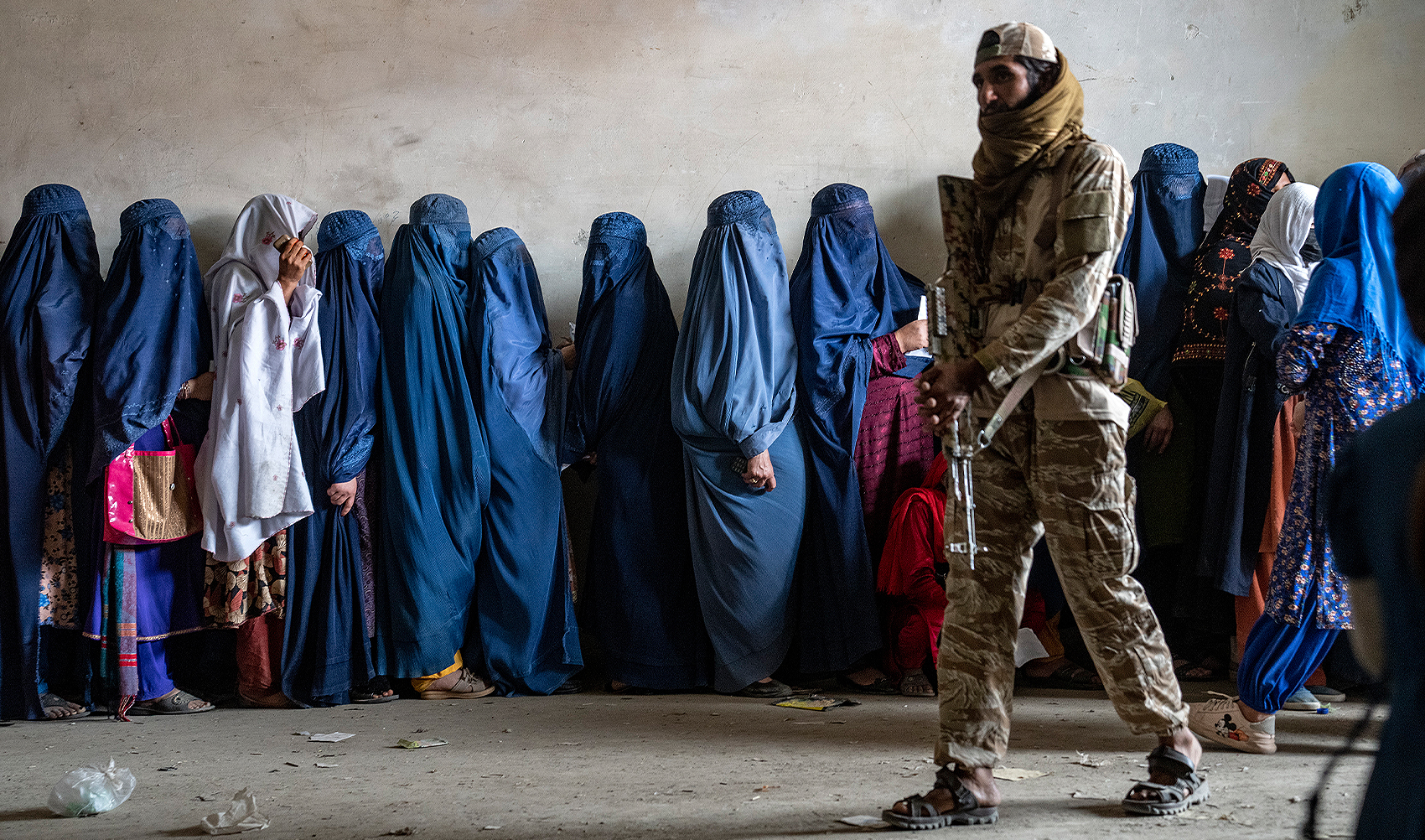 A Taliban fighter stands guard as women wait to receive food rations distributed by a humanitarian aid group, in Kabul, Afghanistan, on May 23, 2023. (AP/File)