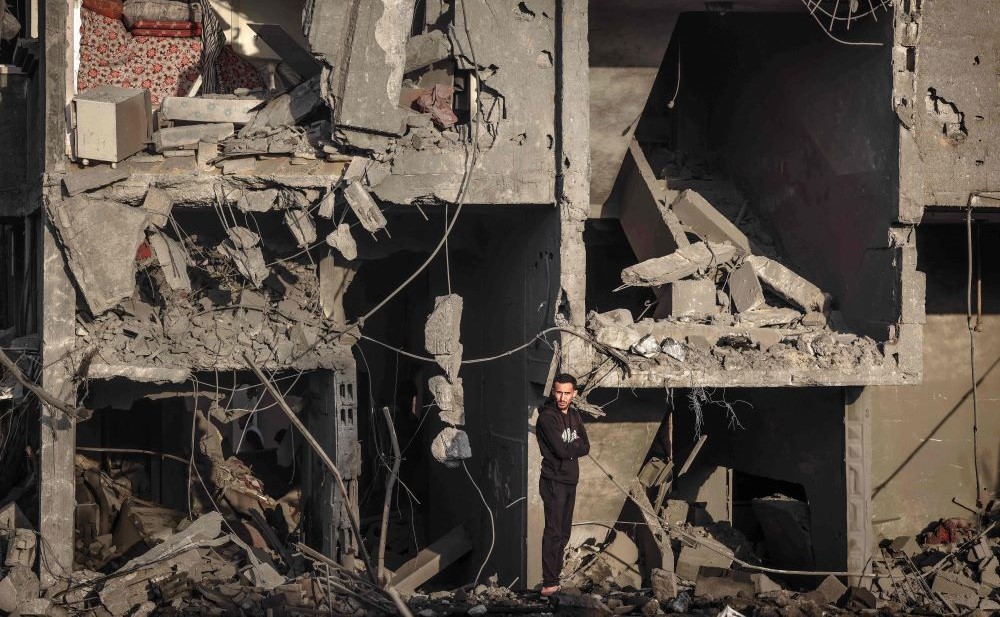 A Palestinian man stands in front of a building destroyed by Israeli strikes, Rafah, southern Gaza Strip, Jan. 24, 2024. (AFP)