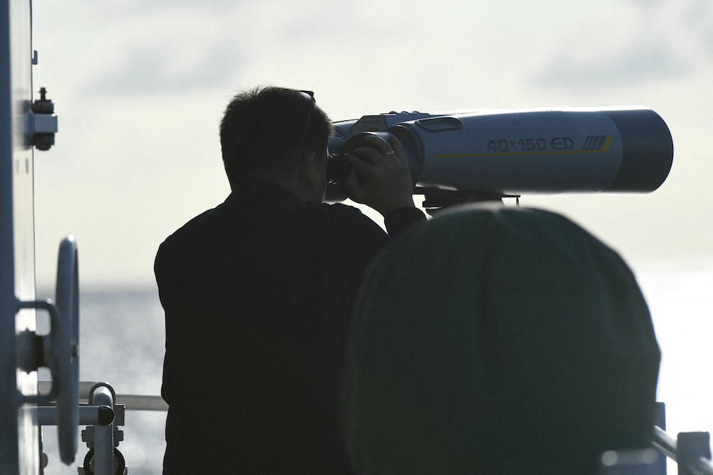 Above, a Philippine coast guard officer monitors a Chinese coast guard ship shadowing a Philippine vessel in the disputed South China Sea on Dec. 10, 2023. (AFP)