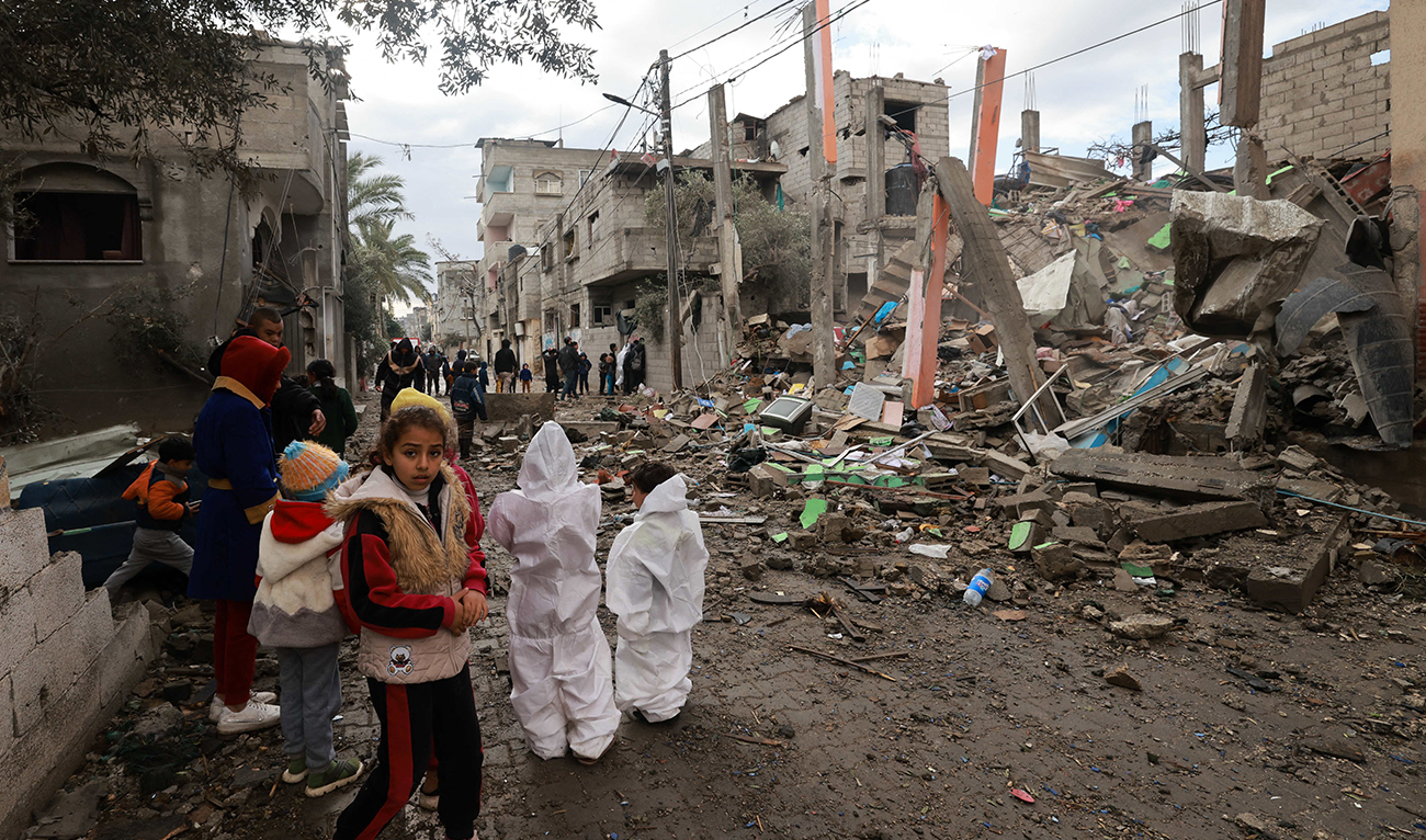 Children gather in front of a building destroyed by Israeli bombing in Rafah in the southern Gaza Strip on January 27, 2024. (AFP)