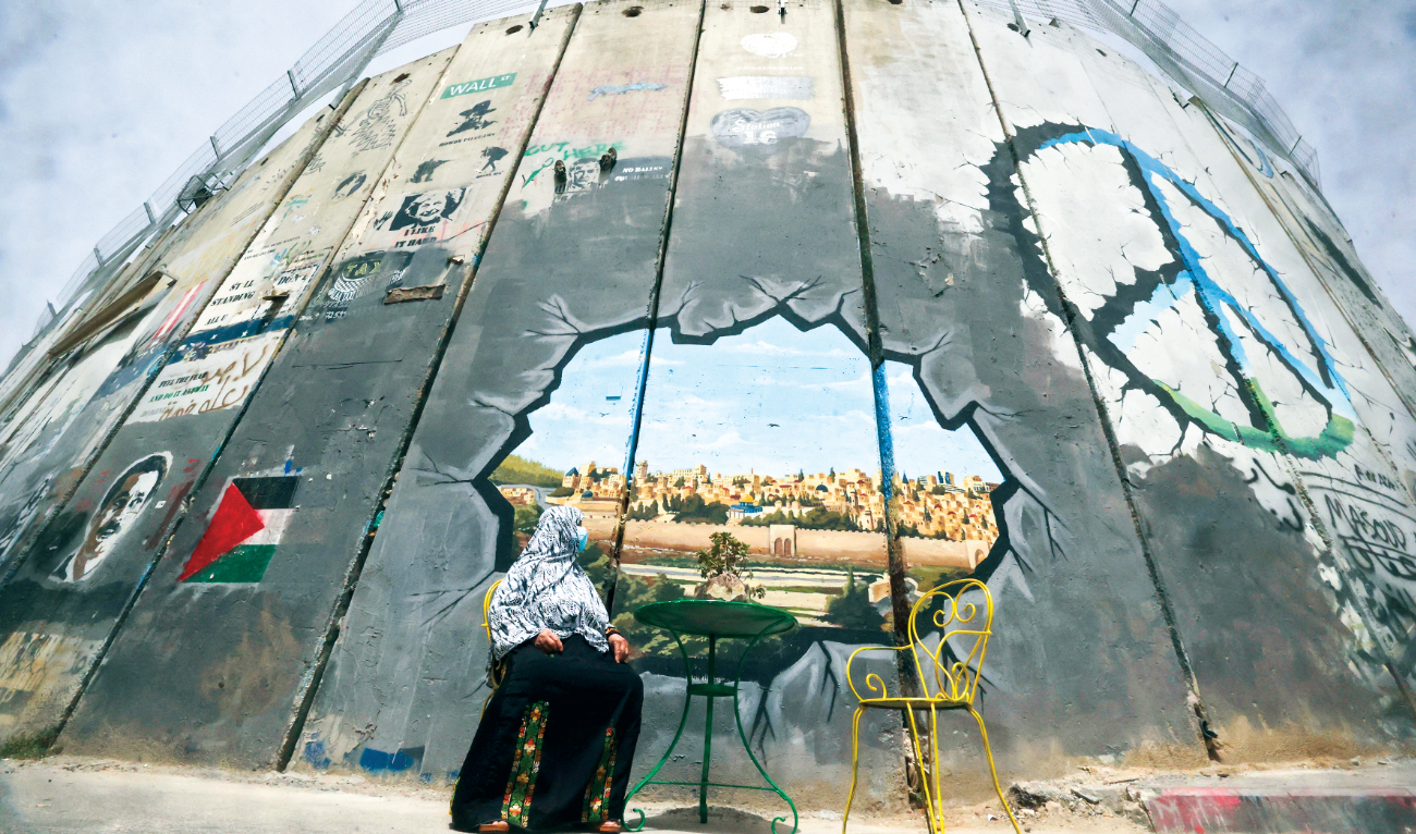 A Palestinian woman looks at a mural depicting Al-Aqsa Mosque compound and Jerusalem’s old city on Israel’s controversial separation barrier between Jerusalem and the occupied West Bank, in Bethlehem on April 17,2022. (AFP)