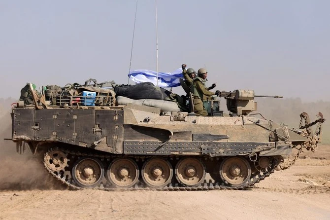 Israeli soldiers on an armoured personnel carrier (APC) waving an Israeli flag as they roll back from the Gaza Strip, amid continuing battles between Israel and the militant group Hamas. (AFP)