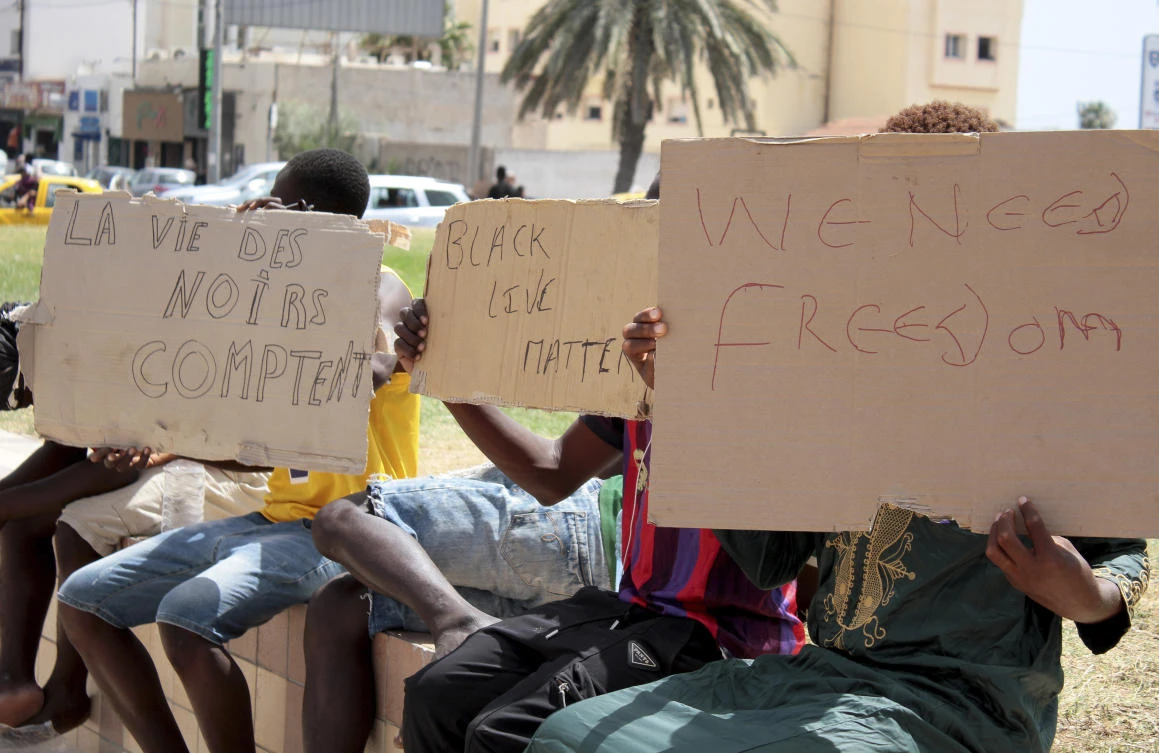Migrants hold placards reading "Black Lives Matter", left, in French, during a gathering in Sfax, Tunisia's eastern coast, on July 7, 2023. (AP)