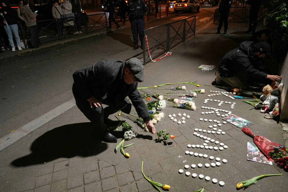 A man lays a flower during a gathering in tribute to victims in front of the Iranian Embassy in Paris on January 4 (AFP)