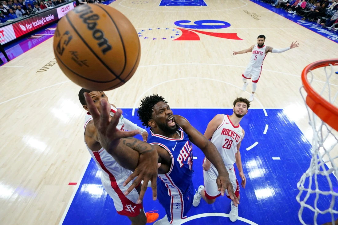 Philadelphia 76ers' Joel Embiid, center, goes up for a shot between Houston Rockets' Jabari Smith Jr., left, and Alperen Sengun during the second half of an NBA basketball game. (AP)
