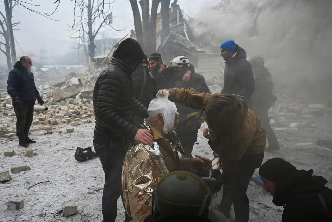 Medical personnel and Ukrainian Law enforcement officers provide medical assistance to a local resident injured as a result of a missile attack in Kharkiv on January 23, 2024. (AFP)