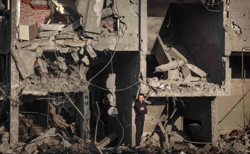 A Palestinian man stands in front of a building destroyed by Israeli strikes, Rafah, southern Gaza Strip, Jan. 24, 2024. (AFP)