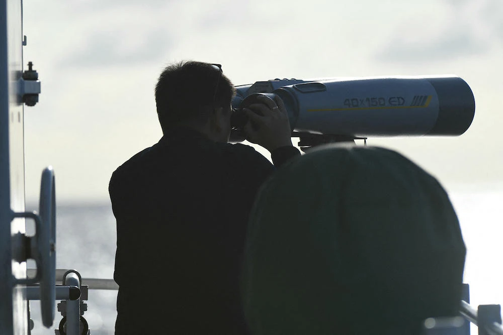 Above, a Philippine coast guard officer monitors a Chinese coast guard ship shadowing a Philippine vessel in the disputed South China Sea on Dec. 10, 2023. (AFP)