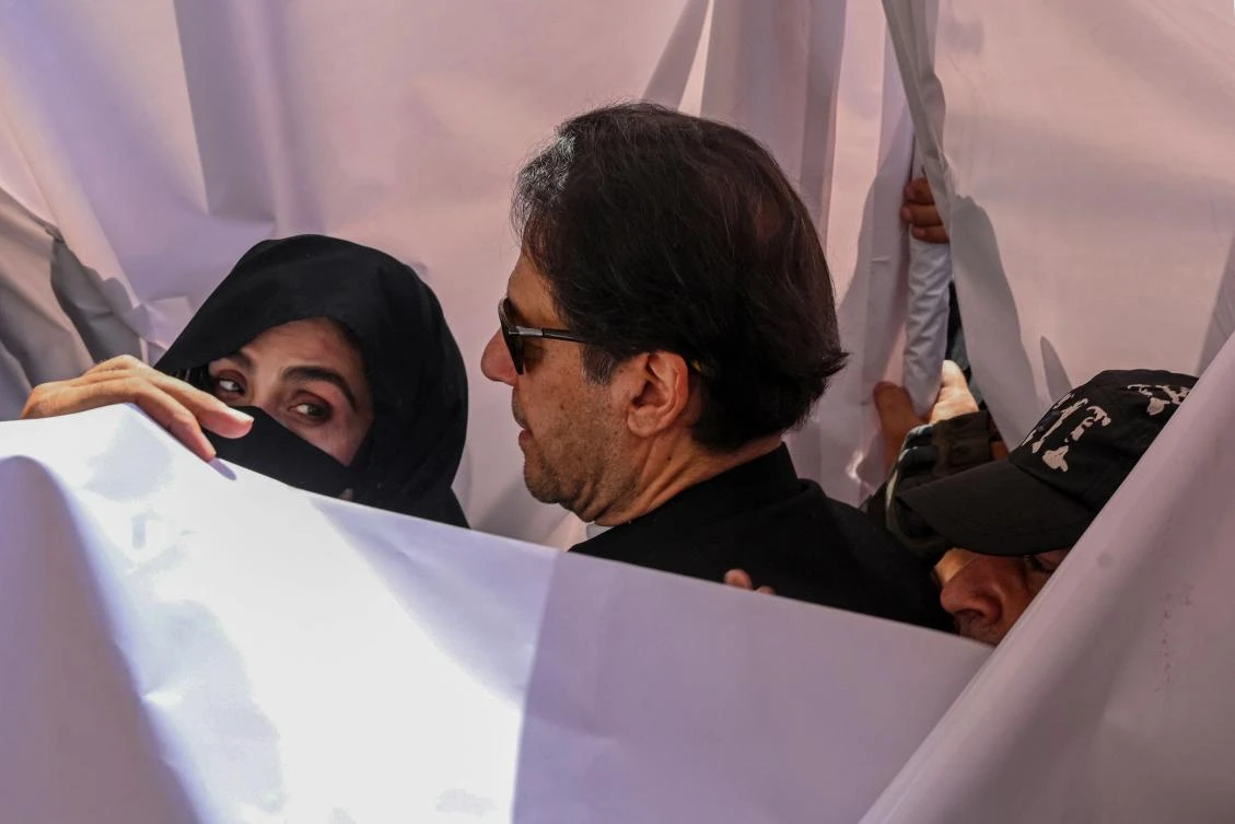 Former Pakistan Prime Minister Imran Khan, center, and his wife Bushra Bibi, left, were sentenced to 14 years for profiting from state gifts sales. (AFP)