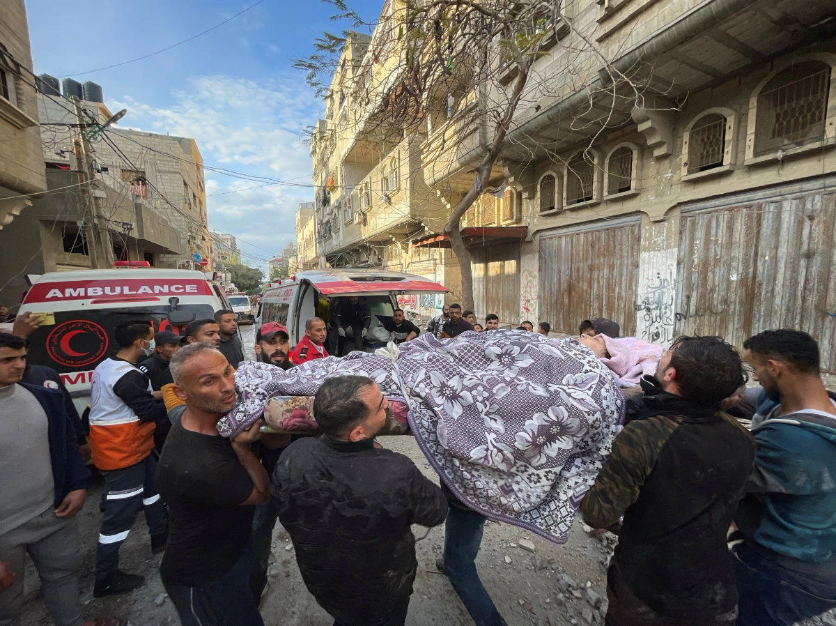 Palestinians carry the body of a woman killed in an Israeli strike at Gaza's Maghazi refugee camp on Jan. 3, 2024. (REUTERS)