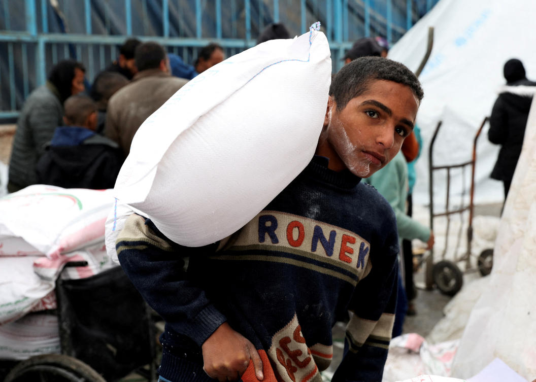 A Palestinian boy carries a bag of flour distributed by UNRWA, amid the ongoing conflict between Israel and Hamas, in Rafah on Jan. 29, 2024. (Reuters)