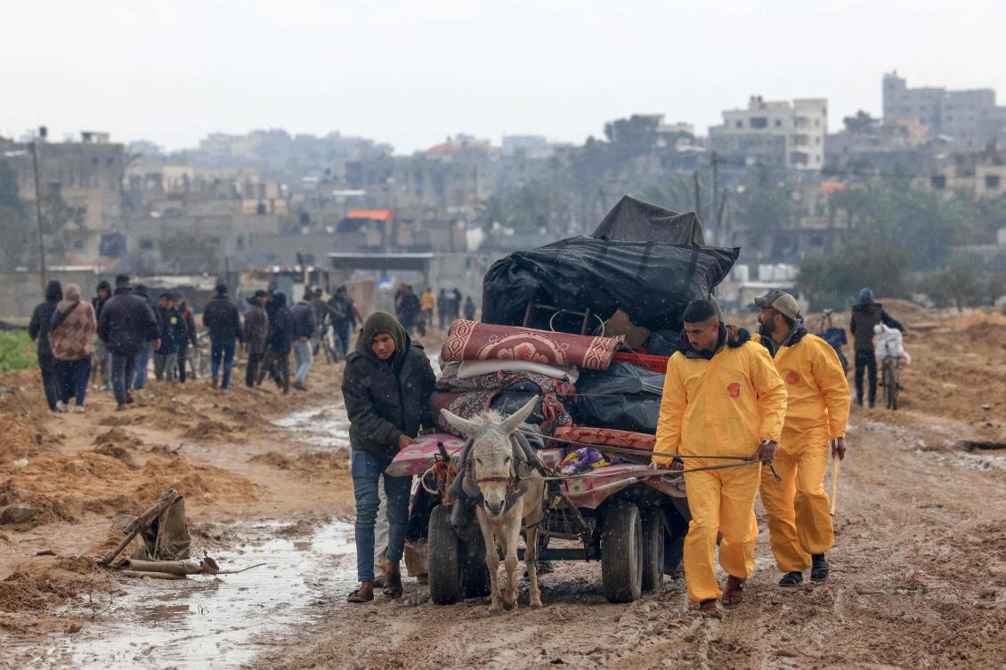 Palestinians, some wearing Hazmat suits left over from the Coronavirus pandemic to keep warm, transport some of their belongings as the flee Khan Yunis in the southern Gaza Strip further south on Feb. 2, 2024. (AFP)
