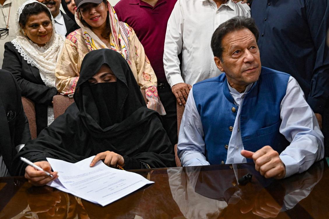 Pakistan’s former Prime Minister, Imran Khan (R) along with his wife Bushra Bibi (L) looks on as he signs surety bonds for bail in various cases, at a registrar office in the High court, in Lahore on July 17, 2023. (AFP/File Photo)
