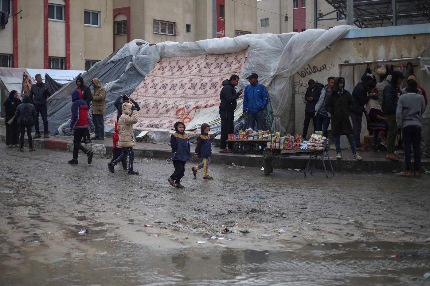 Displaced Palestinians walk past puddles amid rainy weather at a makeshift tent camp in Rafah in the southern Gaza Strip on February 2, 2024. (AFP)