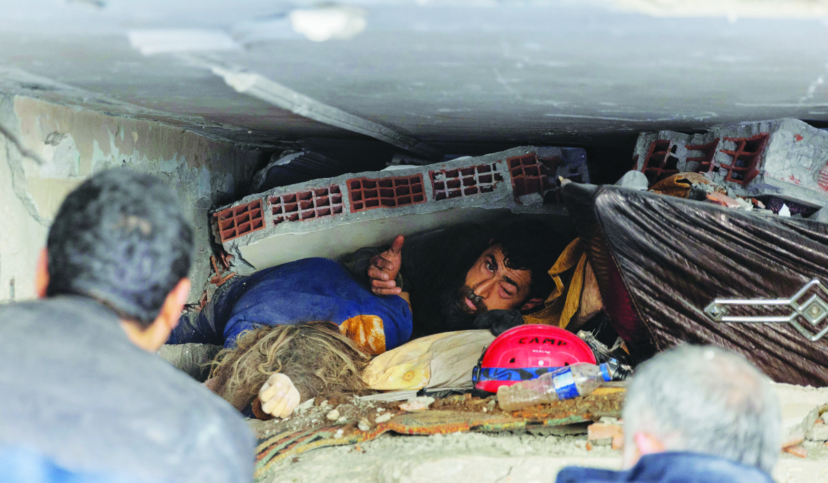 Abdulalim Muaini looks out from under rubble as his wife lies dead next to him in the aftermath of a deadly earthquake in Hatay, Turkey, on February 8, 2023. The quake left millions homeless. (Reuters)