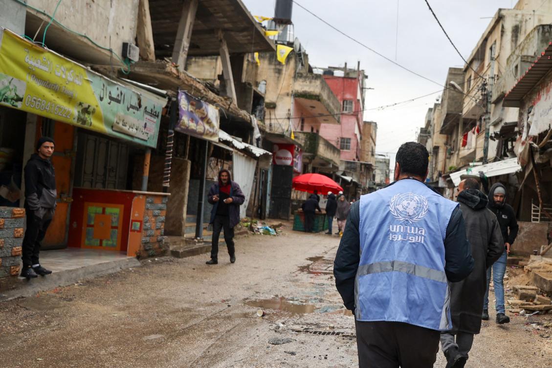 A man wearing a jacket bearing UNRWA logo walks along a street devastated by the passage of Israeli military vehicles and bulldozers during raids in the occupied West Bank on Feb. 4. (AFP)