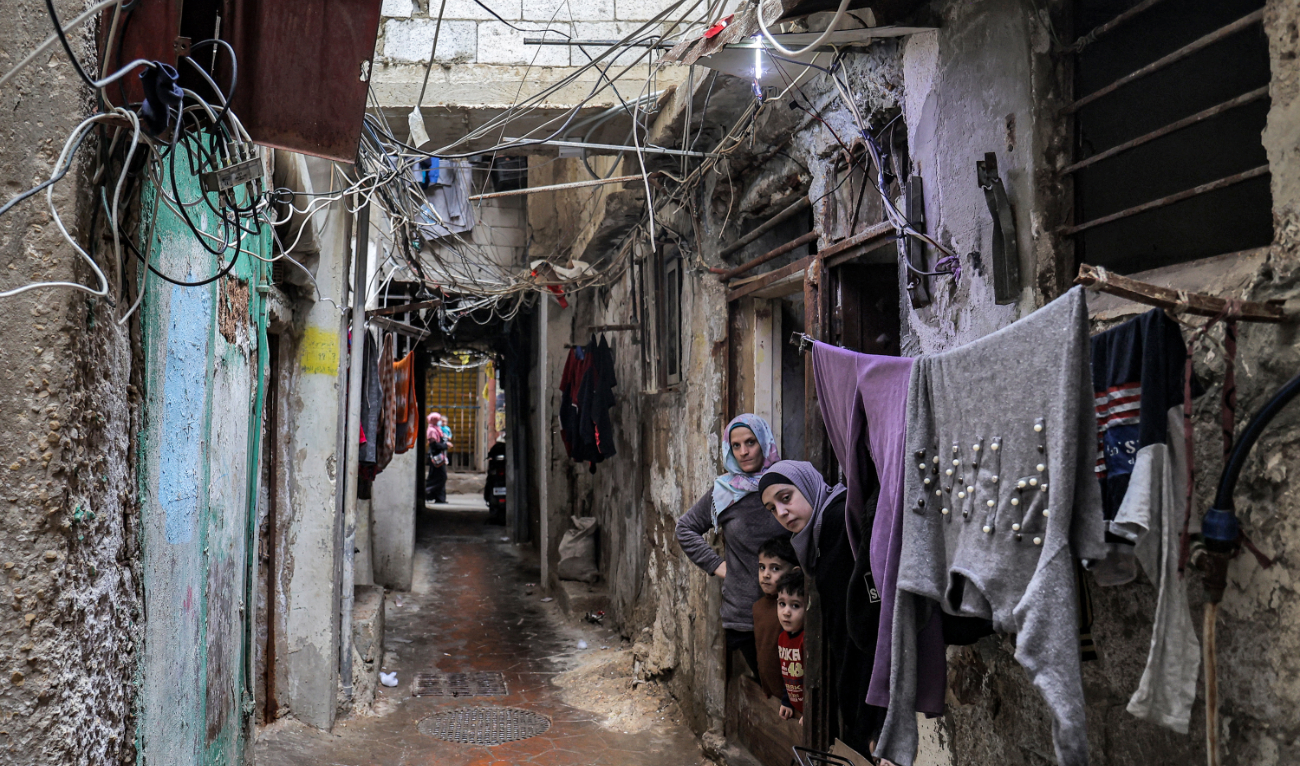 Women look on as they stand outside a home along an alley at the Shatila camp for Palestinian refugees in the southern suburbs of Beirut, on April 19, 2023. (AFP)