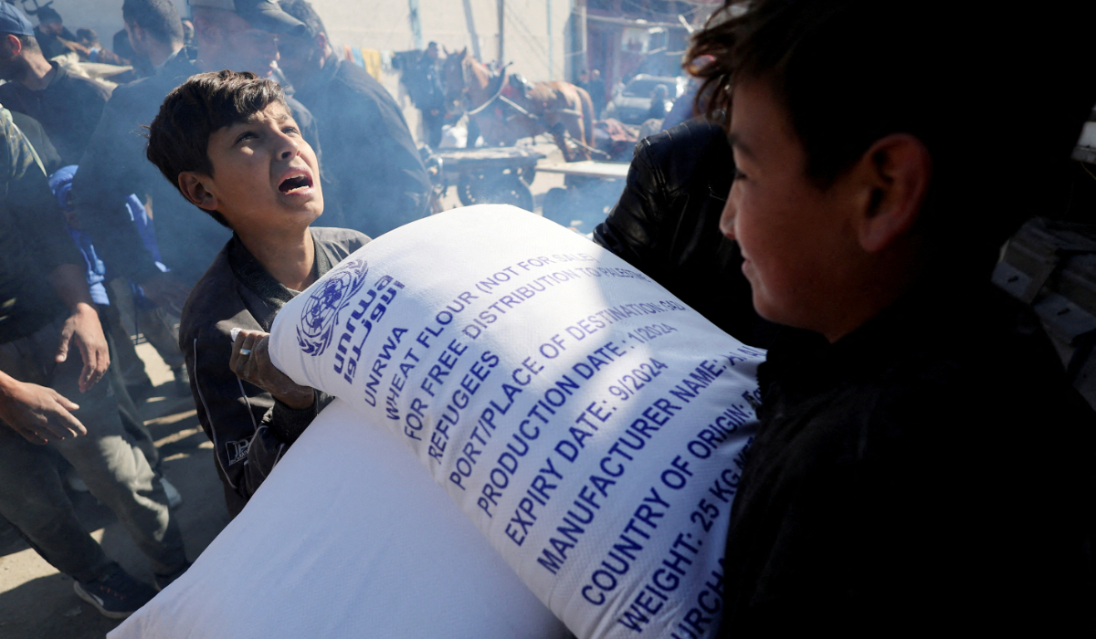 Palestinians gather to receive bags of flour distributed by the United Nations Relief and Works Agency (UNRWA), amid the ongoing conflict between Israel and Palestinian Islamist group Hamas, in Rafah in the southern Gaza Strip February 1, 2024. (REUTERS)